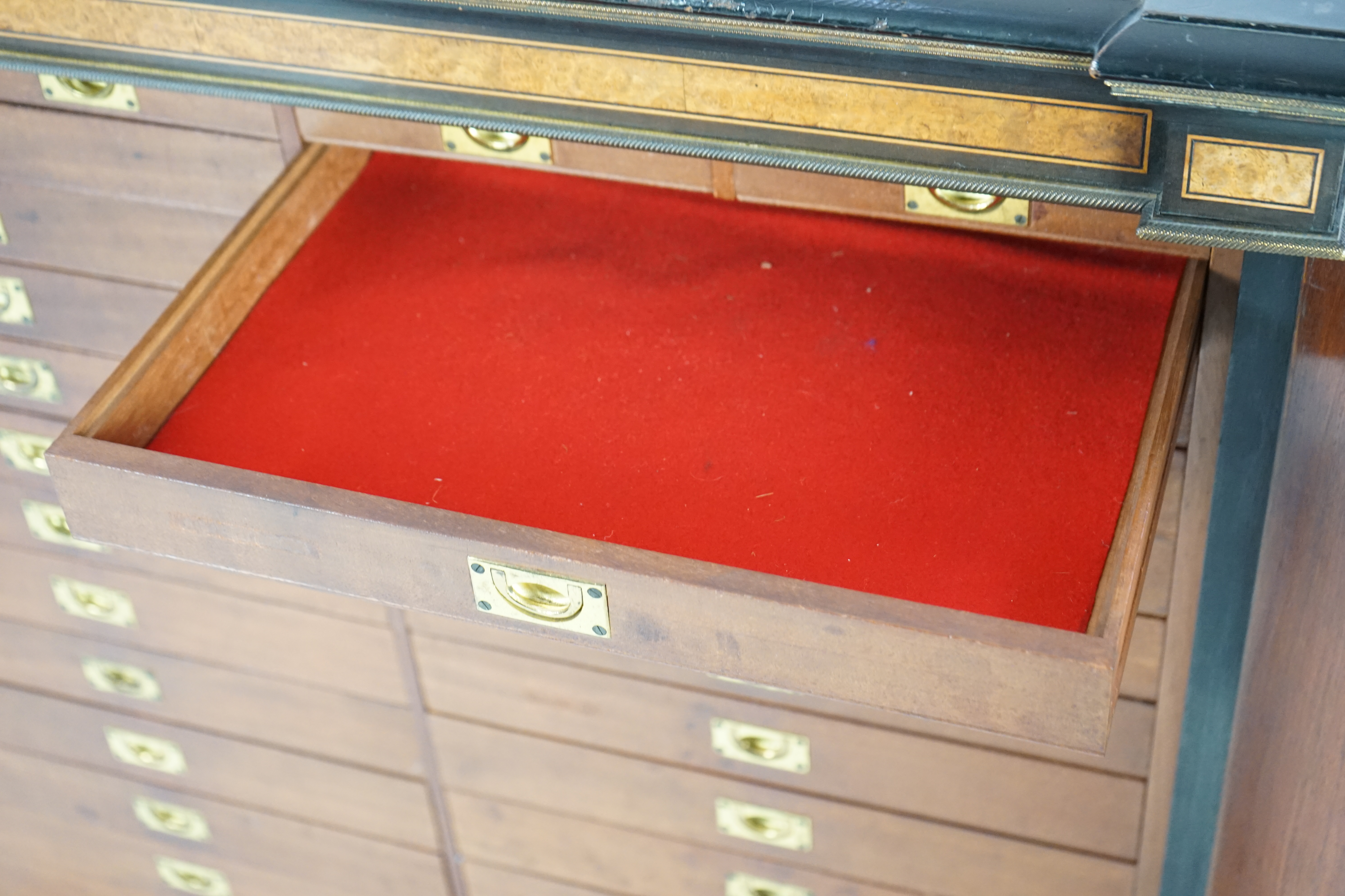 A Victorian ebony banded amboyna wood collector's cabinet, by Holland & Sons, with inverted breakfront top and single mirrored door enclosing four frieze and two banks of thirteen graduated drawers fitted with recessed b